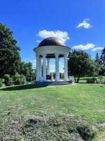 un Kiosko en un parque con arboles y césped foto