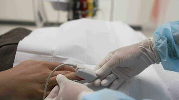 Close up on man's hand with heart rate monitor clipper on finger. The hospital patient is on IV checking the pulse. Hospitalization. Pulse oximeter on finger for monitoring. Heart rate sensor. video