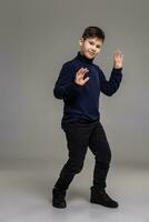 Nice schoolboy is posing at studio over a gray background. photo