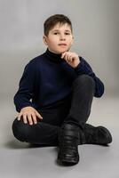 Nice schoolboy is posing at studio over a gray background. photo