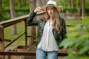 Confident teenage girl standing leaning on iron fence of animal stall in country estate photo