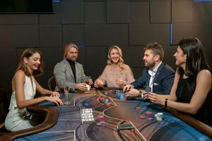 joven personas jugando póker a simpático fiesta, sentado a mesa con tarjetas y alcohol bebidas foto