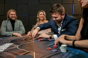 Cheerful bearded guy sitting at poker table in casino and making bet photo