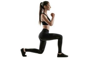 Brunette woman in black leggings, top and sneakers is posing isolated on white. Fitness, gym, healthy lifestyle concept. Full length. photo