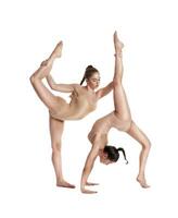 Two flexible girls gymnasts in beige leotards performing complex elements of gymnastics using support, posing isolated on white background. Close-up. photo