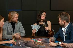 Cheerful young brunette with banknotes and glass of champagne at poker table photo