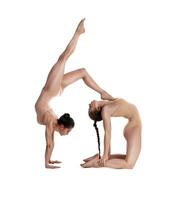 Two flexible girls gymnasts in beige leotards are performing exercises using support and posing isolated on white background. Close-up. photo