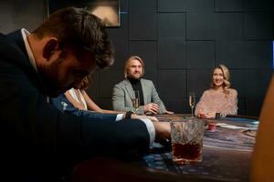 Positive people playing poker at gaming table in casino photo