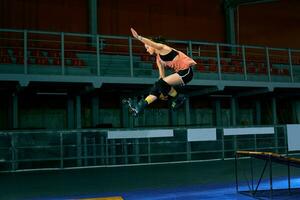 Rollerblader jump high from big air ramp performing trick. Indoors skate park equipment. photo