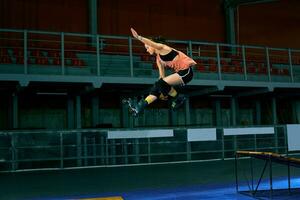 Rollerblader jump high from big air ramp performing trick. Indoors skate park equipment. photo