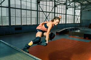 Rollerblader jump high from big air ramp performing trick. Indoors skate park equipment. photo