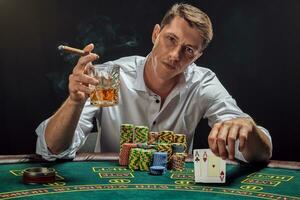 hermoso emocional hombre es jugando póker sentado a el mesa en casino en contra un blanco destacar. foto