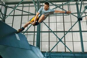 Rollerblader jump high from big air ramp performing trick. Indoors skate park equipment. photo