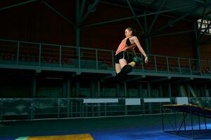 Rollerblader jump high from big air ramp performing trick. Indoors skate park equipment. photo