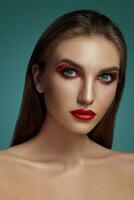 Close-up glamour portrait of a beautiful half-naked model with bright make-up posing over a gray background. photo