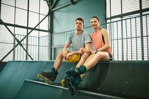 Young man and woman having fun on roller skates in skate park. Hobby photo