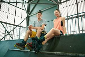 Young man and woman having fun on roller skates in skate park. Hobby photo