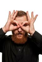 Portrait of a young, chubby, redheaded man in a black shirt making faces at the camera, isolated on a white background photo