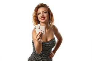 jengibre niña vistiendo gris vestir es posando participación dos jugando tarjetas en su manos en pie aislado en blanco antecedentes. casino, póker. de cerca disparo. foto