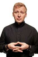 Young blond man in a black shirt, watches and bracelet is making faces, isolated on a white background photo