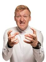 Imposing, young, blond man in a white shirt is grimacing while standing isolated on a white background photo