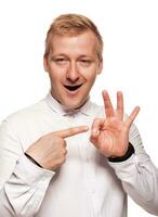 Imposing, young, blond man in a white shirt is grimacing while standing isolated on a white background photo