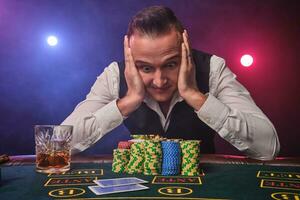 rico hombre es posando a un póker mesa con papas fritas y un vaso de whisky en eso a un casino. foto