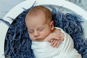 Little baby boy sleeping in a basket on the wooden floor, studio shot photo