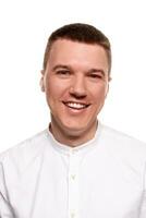 Charming handsome young man in a white shirt is making faces, while standing isolated on a white background photo