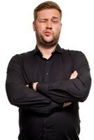 Serious or unhappy young man holding hands crossed and looking at camera in dislike on white background. photo