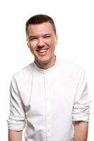 Charming handsome young man in a white shirt is making faces, while standing isolated on a white background photo