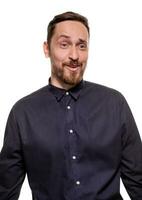 Portrait of a handsome, unshaven man, dressed in a dark blue shirt, standing against a white background. Self confident man. photo