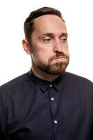 Portrait of a handsome, unshaven man, dressed in a dark blue shirt, standing against a white background. Self confident man. photo