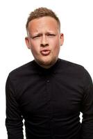 Close up portrait of a confident, blond, handsome young man wearing black shirt, isolated on white background photo