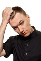 Handsome young man in a black shirt is making faces, while standing isolated on a white background photo