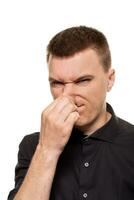 Handsome young man in a black shirt is making faces, while standing isolated on a white background photo