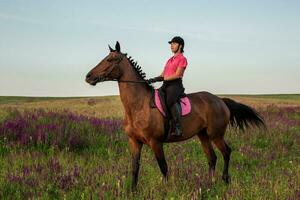 Horsewoman jockey in uniform riding horse outdoors photo