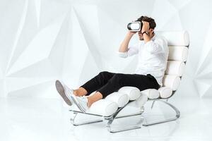 Excited young man is getting experience using VR-headset glasses of virtual reality gesticulating with his hands photo