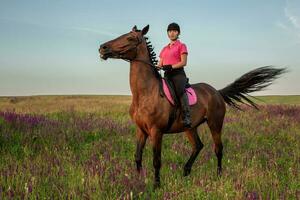 Horsewoman jockey in uniform riding horse outdoors photo