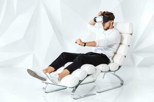 Excited young man is getting experience using VR-headset glasses of virtual reality gesticulating with his hands photo