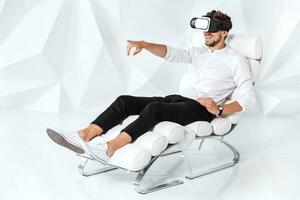 Excited young man is getting experience using VR-headset glasses of virtual reality gesticulating with his hands photo