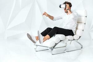 Excited young man is getting experience using VR-headset glasses of virtual reality gesticulating with his hands photo