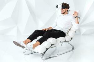 Excited young man is getting experience using VR-headset glasses of virtual reality gesticulating with his hands photo