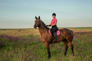 Horsewoman jockey in uniform riding horse outdoors photo