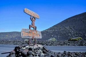 a sign on the side of a road with a mountain in the background photo