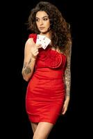 Confident young woman in red dress holding pair of aces photo
