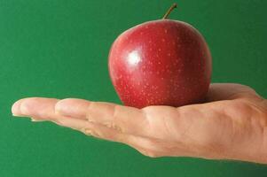 un mano participación un manzana en un verde antecedentes foto