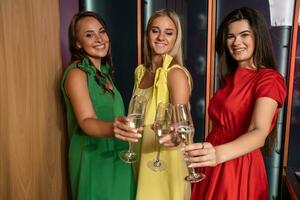 Tres contento simpático muchachas tintinamente champán a hogar despedida de soltera fiesta foto