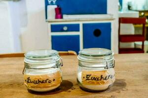 two jars with labels on them sitting on a wooden table photo