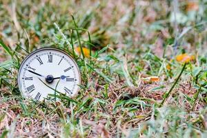 an old clock is sitting in the grass photo